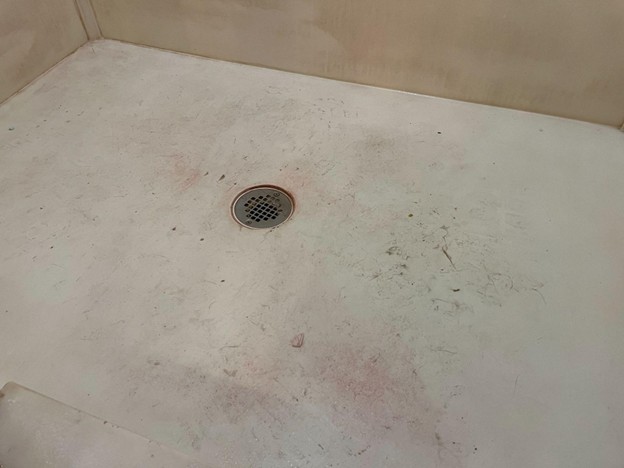 Worn shower floor with stains and drainage buildup